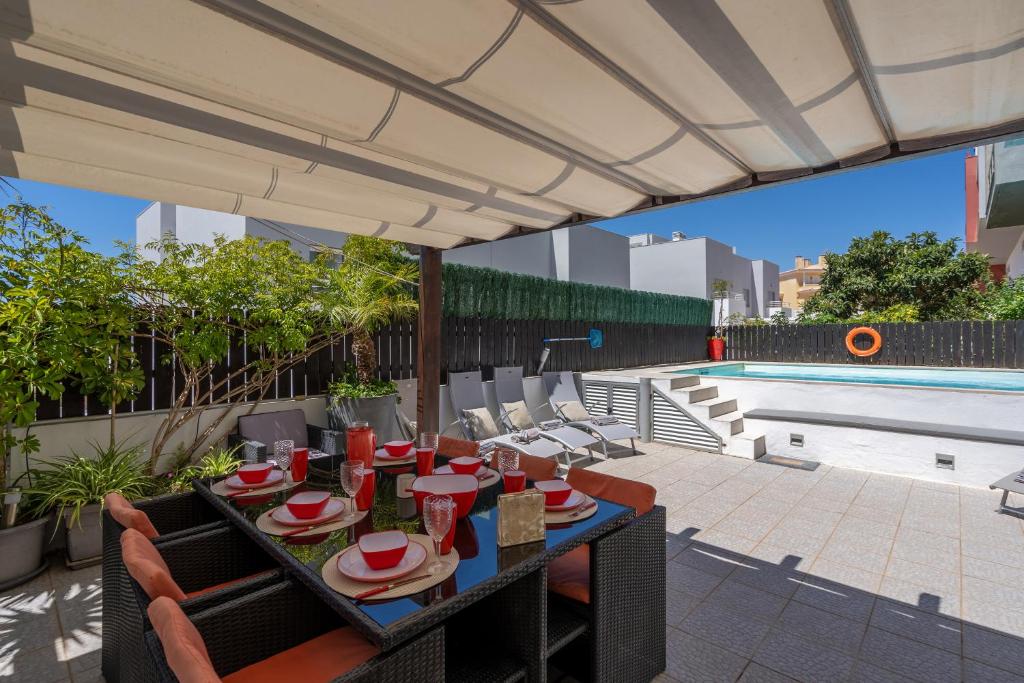 a patio with a table and chairs and a pool at Vila Cantinho Algarvio Vista Rio in Ferragudo
