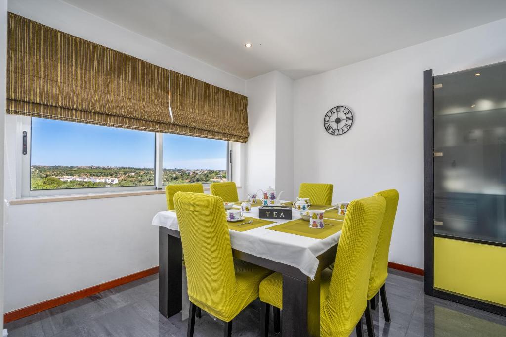 a dining room with a table and yellow chairs at Vila Cantinho Algarvio Vista Rio in Ferragudo