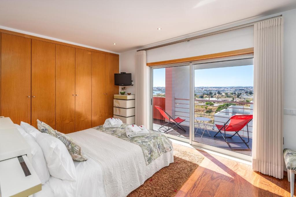 a bedroom with a bed and a balcony with a television at Vila Cantinho Algarvio Vista Rio in Ferragudo