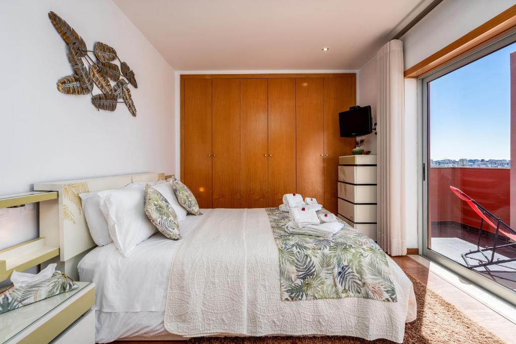 a bedroom with a bed and a large window at Vila Cantinho Algarvio Vista Rio in Ferragudo