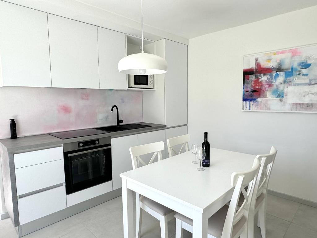una cucina bianca con tavolo e sedie bianchi di ArtApArt T a Rabac