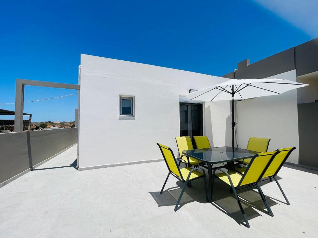 a table with yellow chairs and an umbrella on a roof at Lafo Rooms in Elafonisi