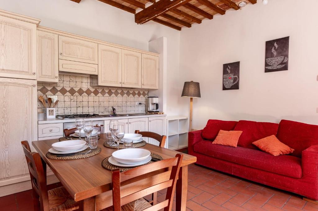 a living room with a table and a red couch at Residenza il Vicolo del Corso in Massa Marittima