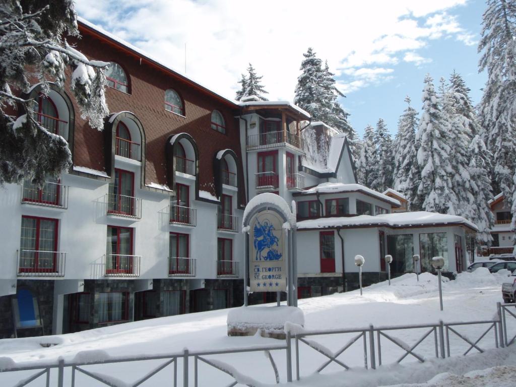 a building with snow on the ground in front of it at Saint George Borovets Hotel in Borovets