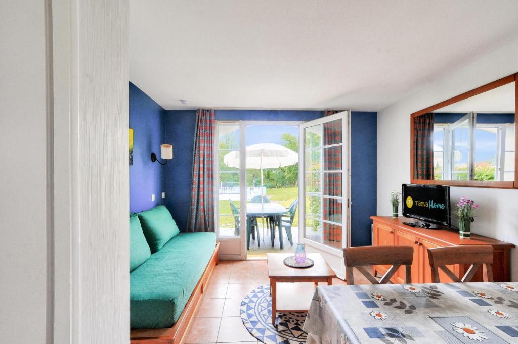 un salon avec un canapé vert et une table dans l'établissement La résidence du Lac - maeva Home - Maison 3 pièces 6 personnes - Sélection MAE-8131, à Monflanquin