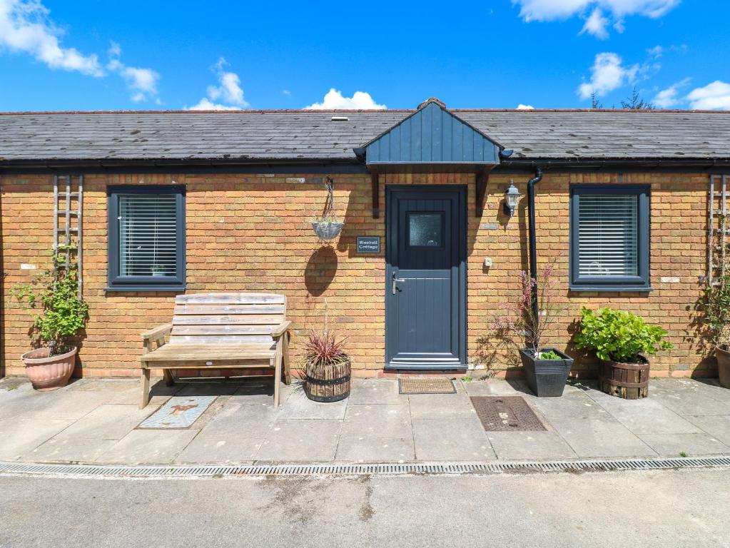 a brick house with a bench in front of it at Bluebell Cottage in Cardiff