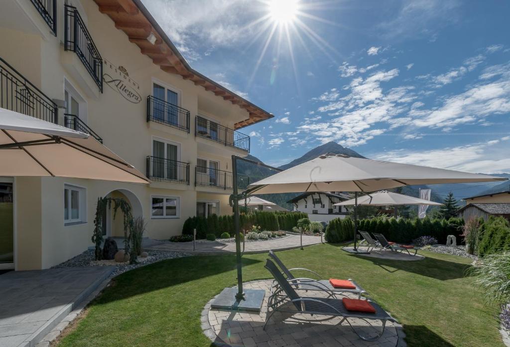 a patio with chairs and an umbrella in front of a building at Residenz Allegra in Sölden