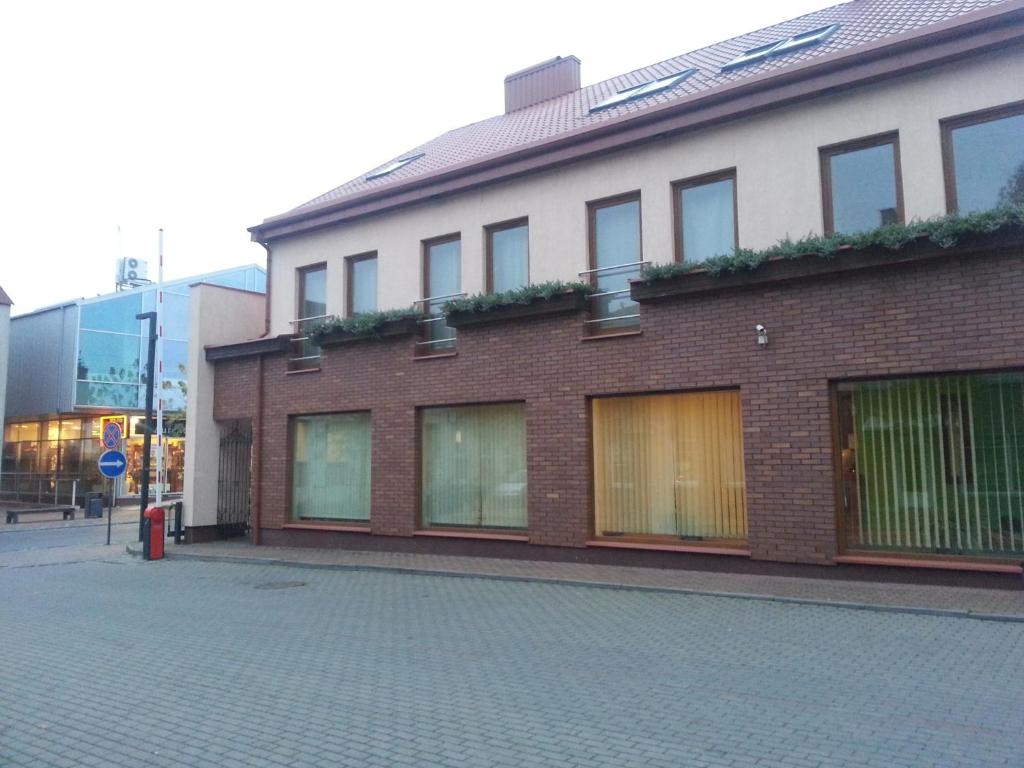a brick building with windows on a street at Keta in Marijampolė