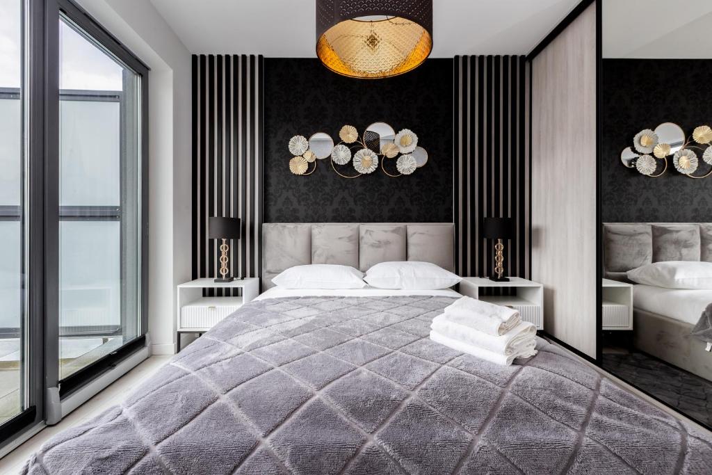 a bedroom with a large bed and two windows at ApartPort nowoczesne apartamenty in Gdynia