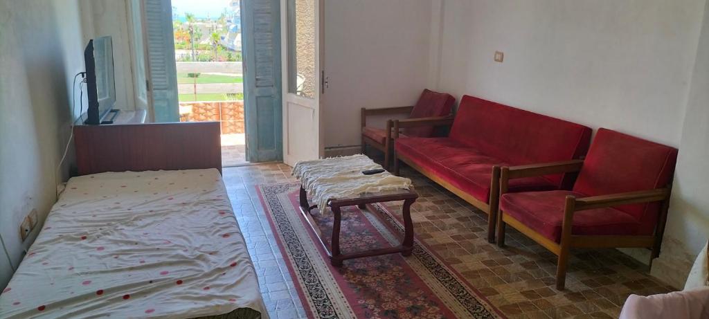a living room with a red couch and a table at Marakia beach in Dawwār ‘Abd al Qādir Qāsim