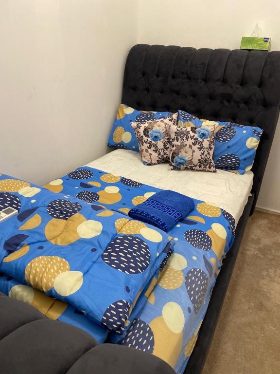 łóżko z niebiesko-żółtą kołdrą i poduszkami w obiekcie BYC Homes w Abu Zabi