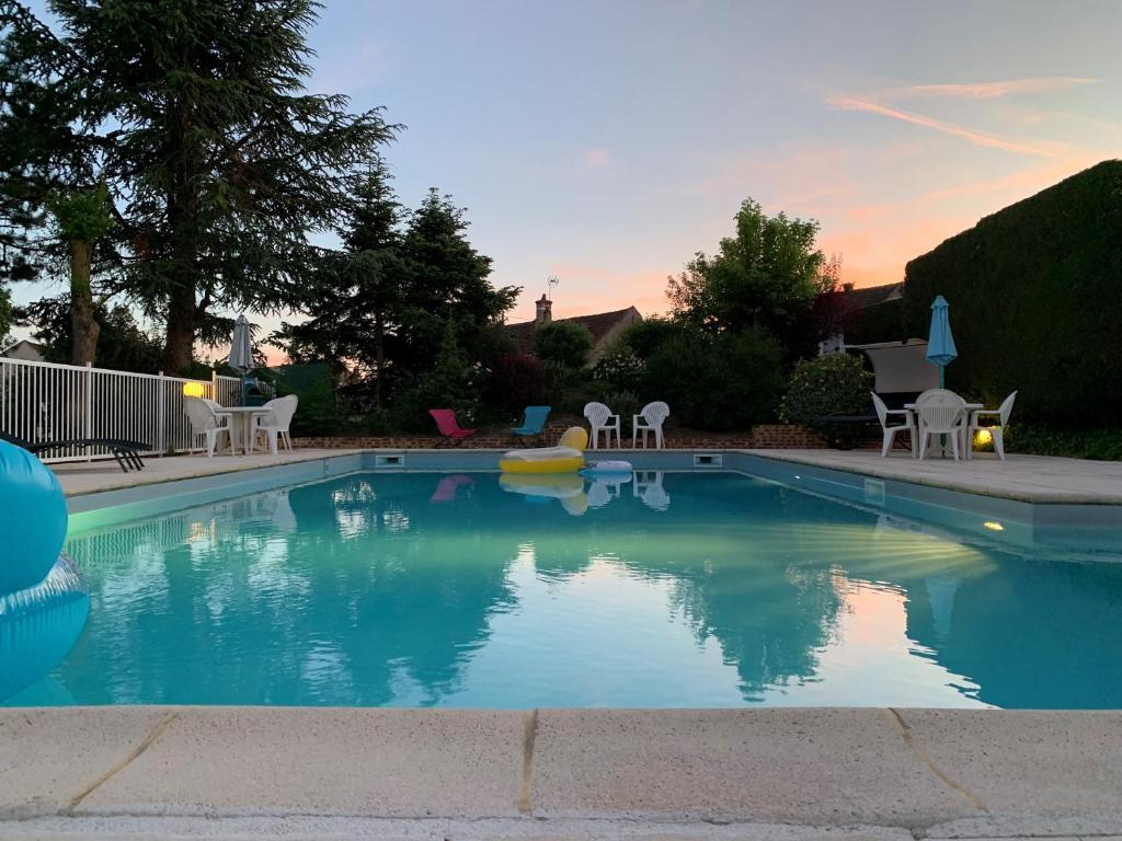 a swimming pool with tables and chairs in a yard at Brit Hotel Dak Hotel in Avallon
