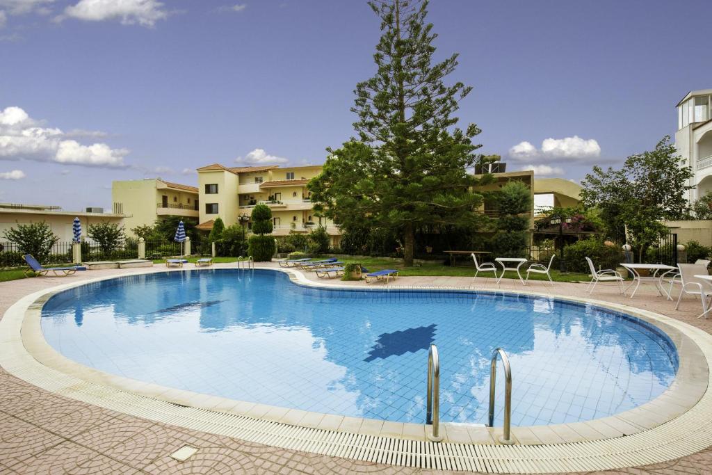 a large blue swimming pool with chairs and tables at Lyristis Dinos Studios & Apartments in Faliraki