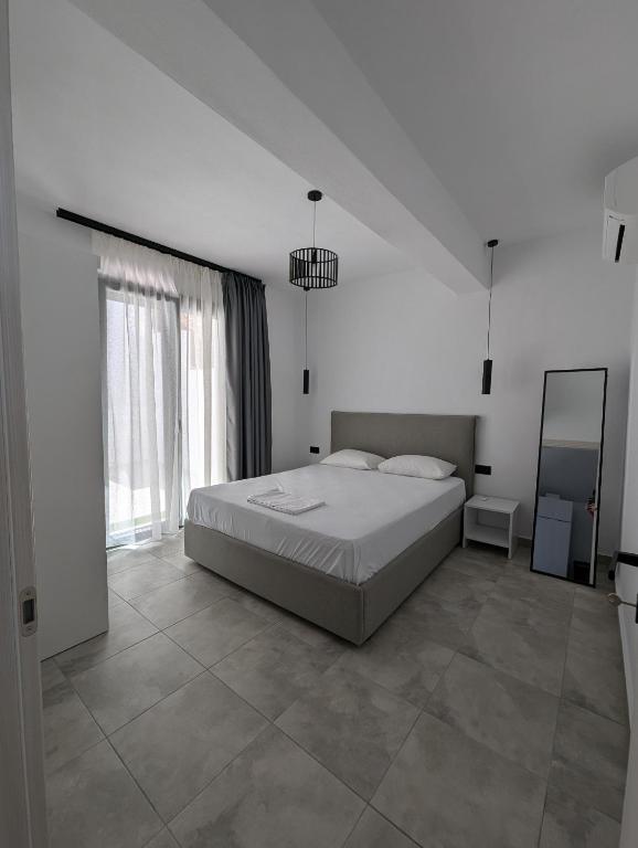 a white bedroom with a bed and a mirror at Villa Selini in Skala Potamias
