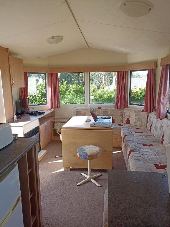 Il comprend une cuisine et un salon avec un bureau et un canapé. dans l'établissement Mobil-home 4 à 6 personnes camping paradis 4 étoiles, à Clohars-Carnoët