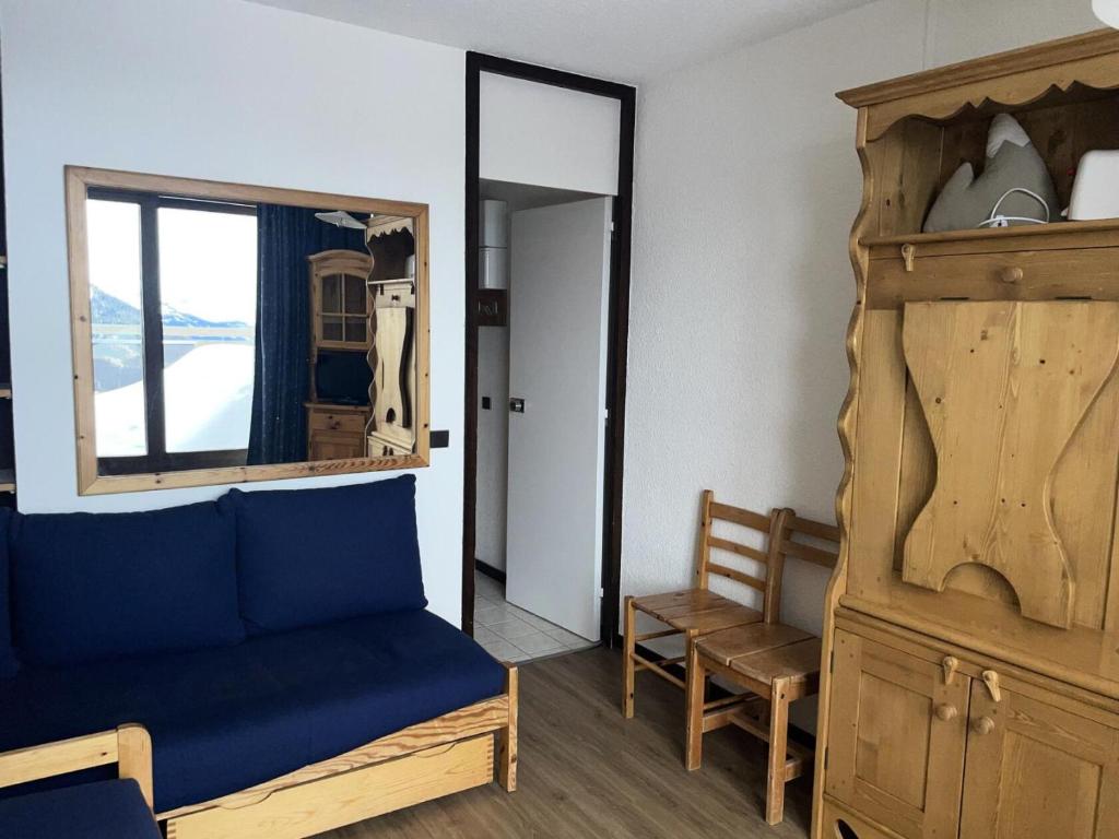 une chambre avec un canapé bleu et un miroir dans l'établissement Résidence Etoile - Studio pour 2 Personnes 524, à La Plagne Tarentaise