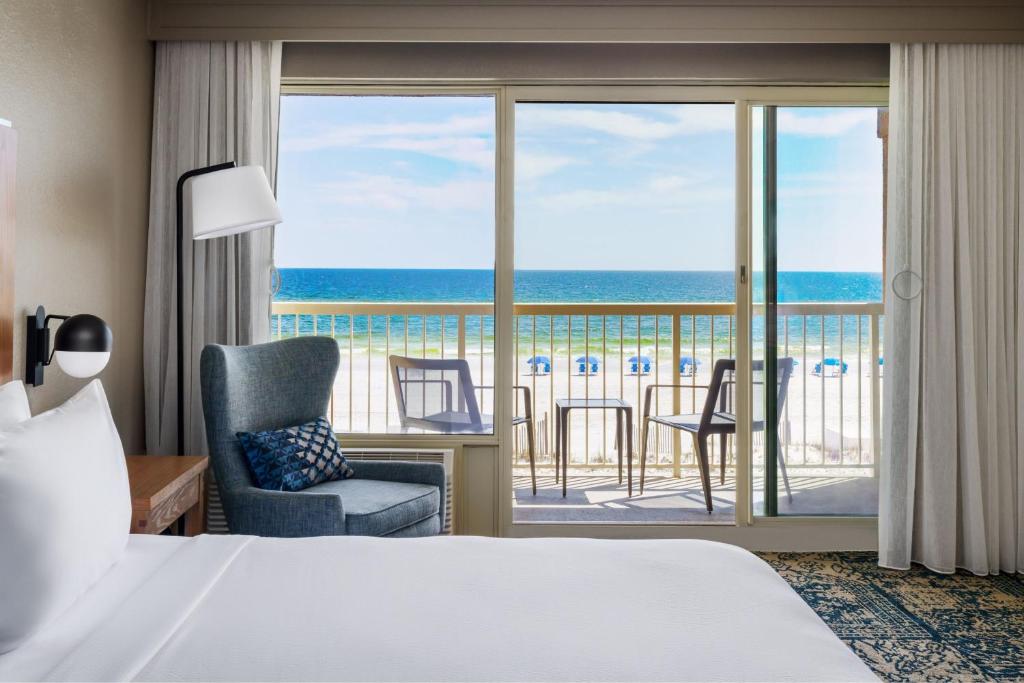 a hotel room with a bed and a balcony with the ocean at Four Points by Sheraton Destin - Fort Walton Beach in Fort Walton Beach