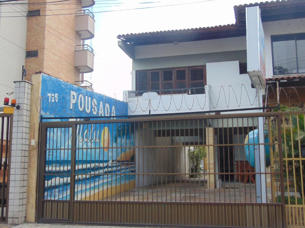 a fence in front of a house with a sign at Pousada Malu in Fortaleza