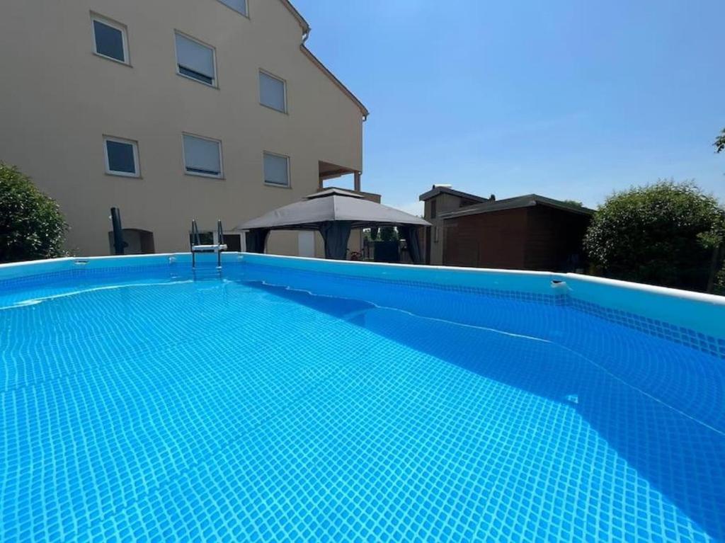 a blue swimming pool in front of a building at Apartment Bellevue in Vodnjan