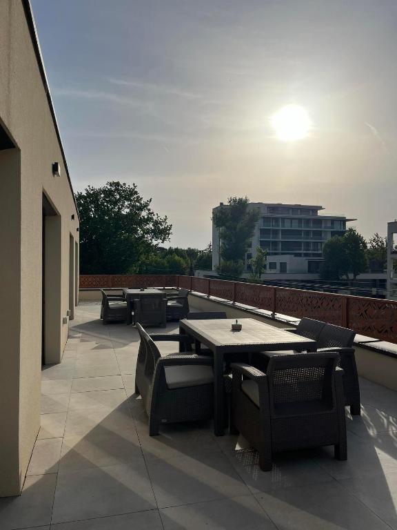 a patio with a table and chairs on a roof at Lux Penthouse Balatonlelle in Balatonlelle