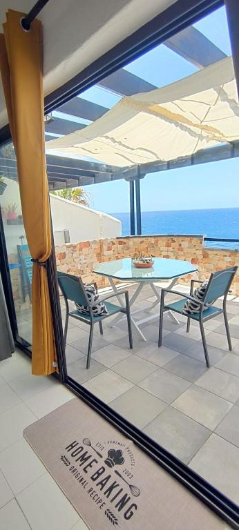 a patio with a table and chairs and a view of the ocean at El retiro azul in Gáldar