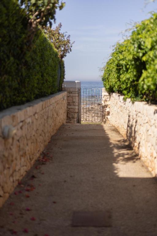 a sidewalk next to a stone wall with the ocean at Tufara Villa a Mare in Polignano a Mare