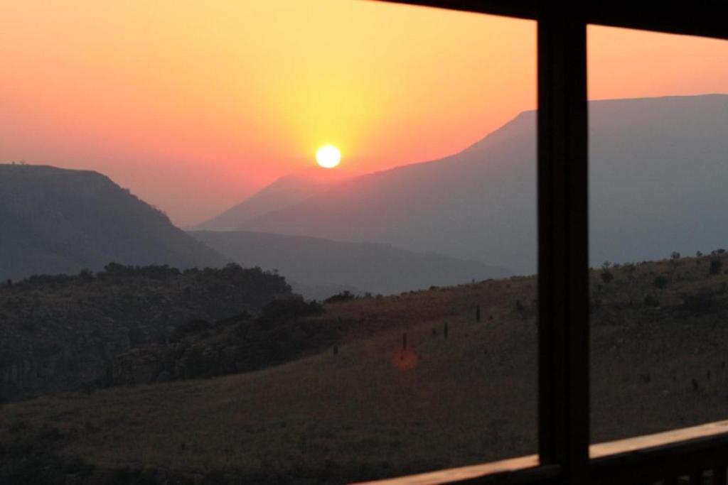 una ventana con vistas a la puesta de sol en Acra-Retreat Mountain View Lodge, en Waterval Boven