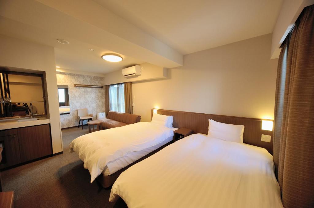 een hotelkamer met 2 bedden en een bank bij Dormy Inn Express Meguro Aobadai Hot Spring in Tokyo