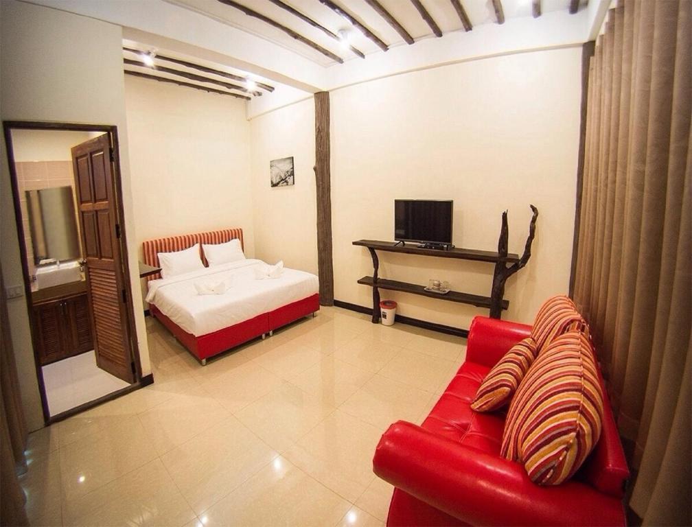 a living room with a red couch and a bed at Rao Ga Khao Resort in Mu Si