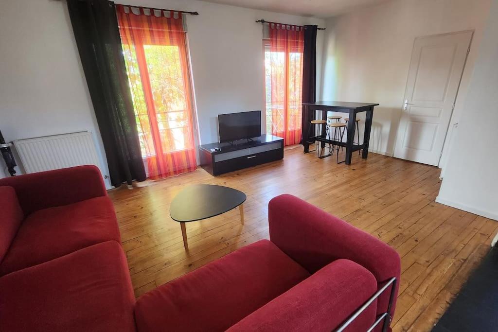 un salon avec un canapé rouge et une télévision dans l'établissement T3 moderne hyper centre parking privé, à Toulouse