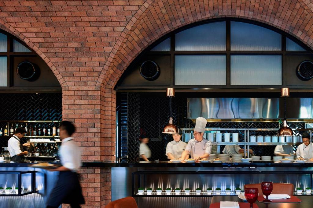An open restaurant kitchen where chefs prepare food behind a brick-arched counter.