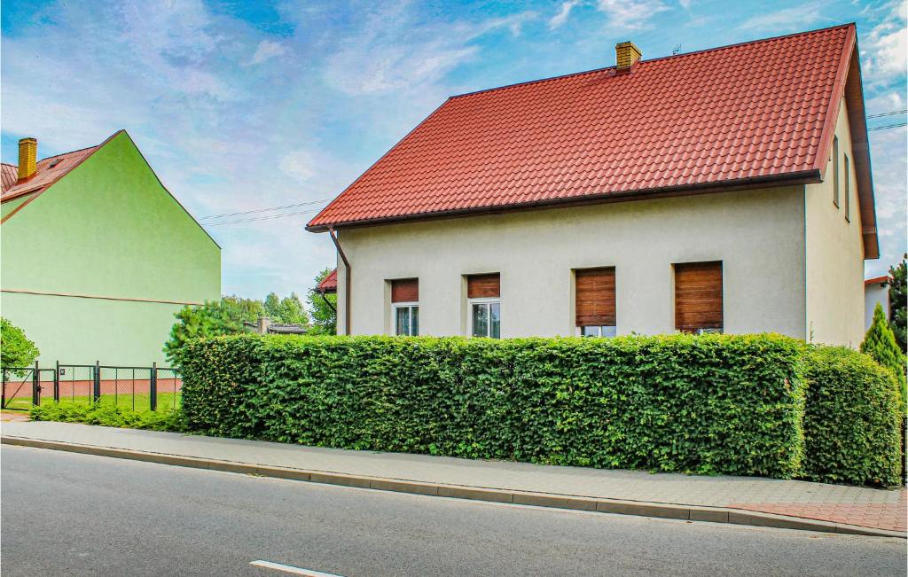 a house with a red roof next to a hedge at Two-Bedroom Holiday Home In Osno Lubuskie in Ośno Lubuskie