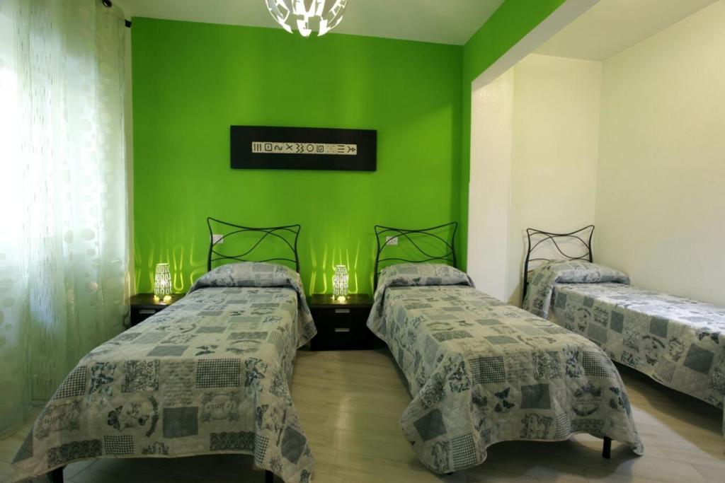 a room with three beds with green walls at Appartamenti Romatour in Rome