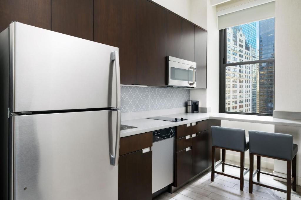 a kitchen with a refrigerator and two chairs at Residence Inn by Marriott New York Downtown Manhattan/World Trade Center Area in New York