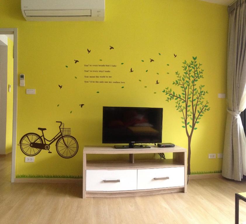 uma sala de estar com televisão e uma bicicleta na parede em Baan San Kraam em Cha Am