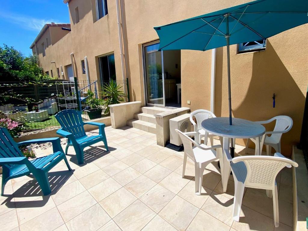 un patio avec des chaises et une table avec un parasol dans l'établissement Studio Coquet à Mèze : Climatisé, Près du Parc, Terrasse, Proche Plage et Port - FR-1-604-51, à Mèze