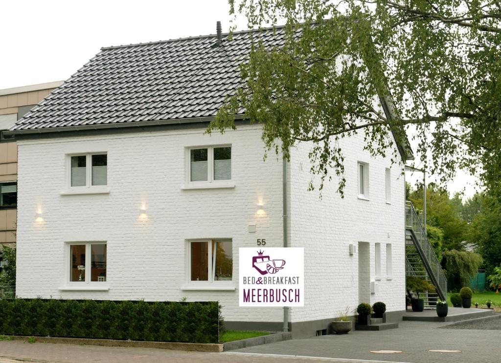 una casa blanca con un cartel delante en Bed & Breakfast Meerbusch en Meerbusch