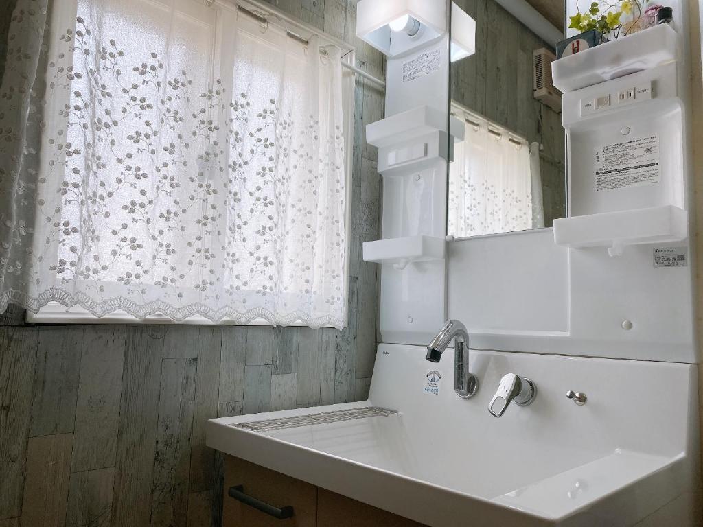 une salle de bains avec un lavabo et un miroir dans l'établissement Ryokan Sansui, à Furano