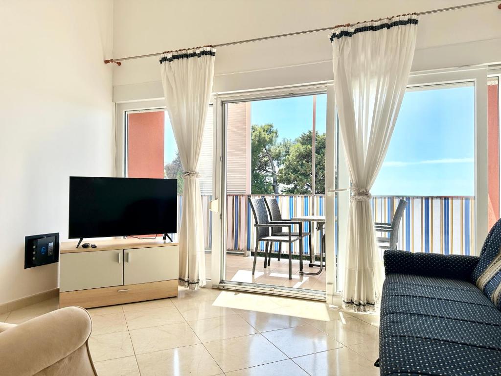 a living room with a couch and a television and a balcony at Apartment Elaine's View in Umag