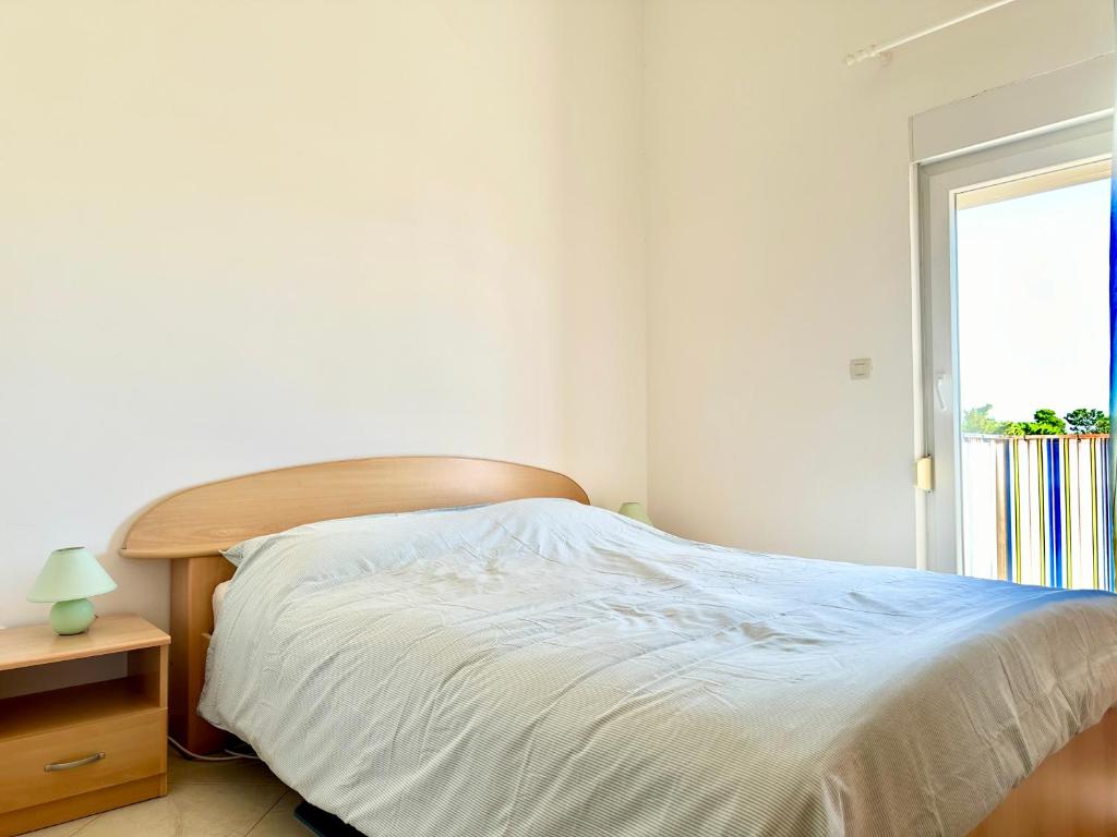 a white bedroom with a bed and a window at Apartment Elaine's View in Umag