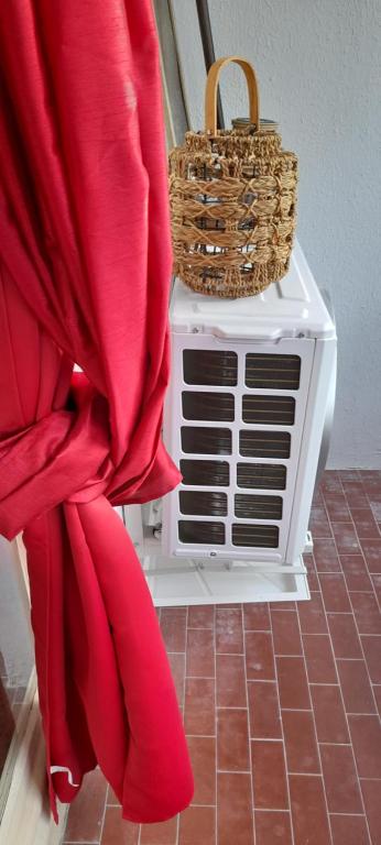 un rideau rouge avec un panier au-dessus d'un radiateur dans l'établissement Le Kiowas CARNON PLAGE, à Carnon-Plage