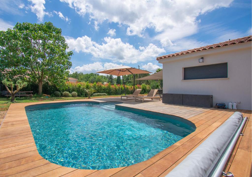 - une piscine sur une terrasse en bois à côté d'une maison dans l'établissement Maison 110m2, piscine, 3ch, à Callian