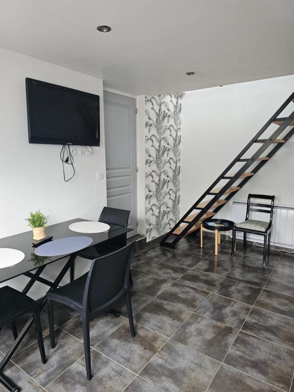a living room with a table and chairs and a tv at Appartement entre Terre et Mer in Prat