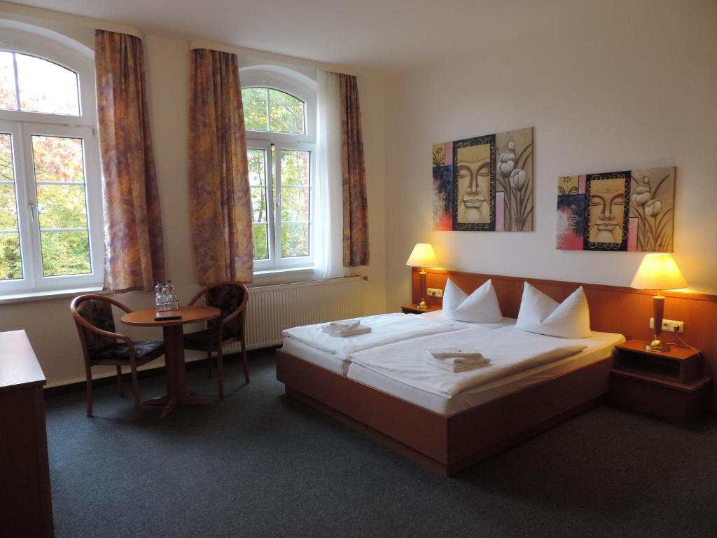 um quarto com uma cama, uma mesa e janelas em Hotel Carl von Clausewitz em Burg bei Magdeburg