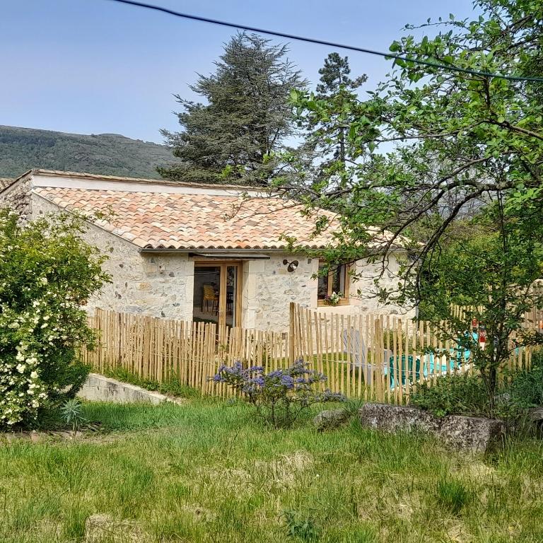 une petite maison en pierre avec une clôture en bois dans l'établissement La Grange, à Saint-Vincent-de-Barrès