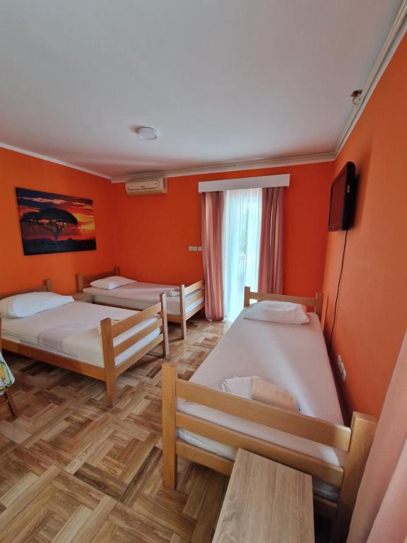 pokój z trzema łóżkami i pomarańczowymi ścianami w obiekcie Pool Apartments Knežević Novalja w Novalji