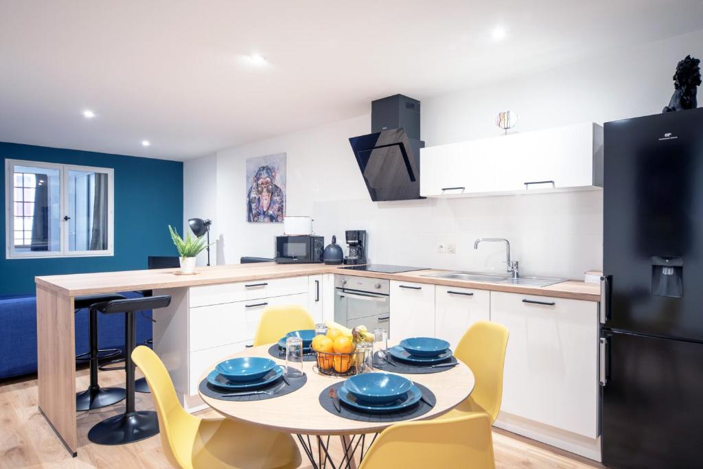 une cuisine avec une table, des chaises et un réfrigérateur dans l'établissement MyAppart71 - La préfecture - Appartement en Coeur de Ville, à Mâcon