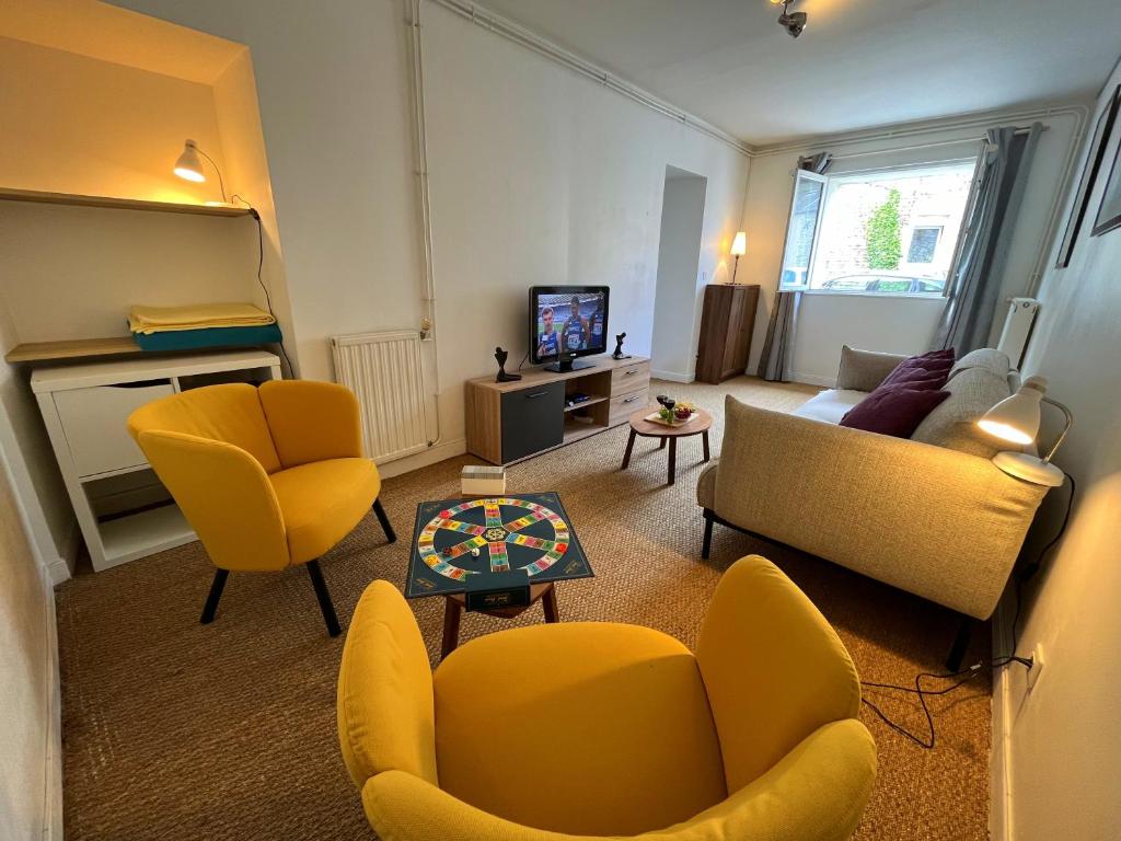 un salon avec des chaises jaunes et une télévision dans l'établissement Écurie des Charmes à 5 minutes de la plage, à Merville-Franceville-Plage