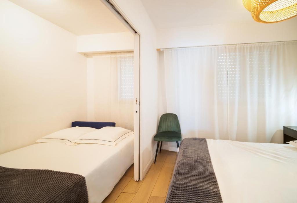 a bedroom with two beds and a green chair at Sunny Days in Nice