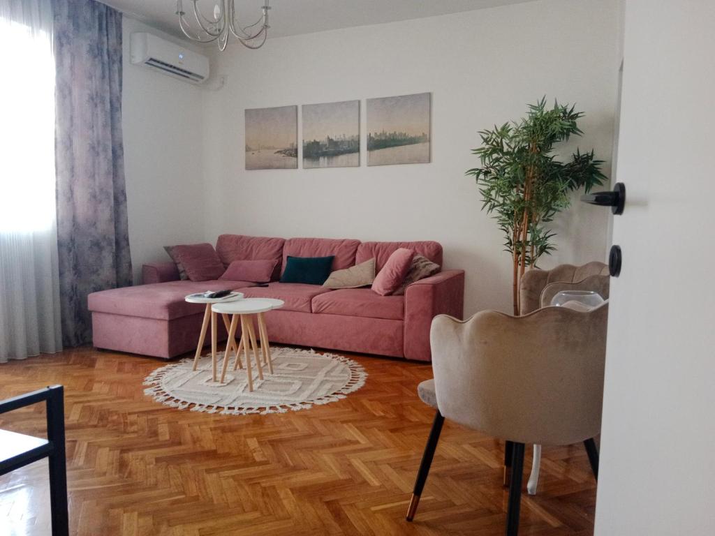 a living room with a pink couch and a table at Serenity City Centre in Podgorica